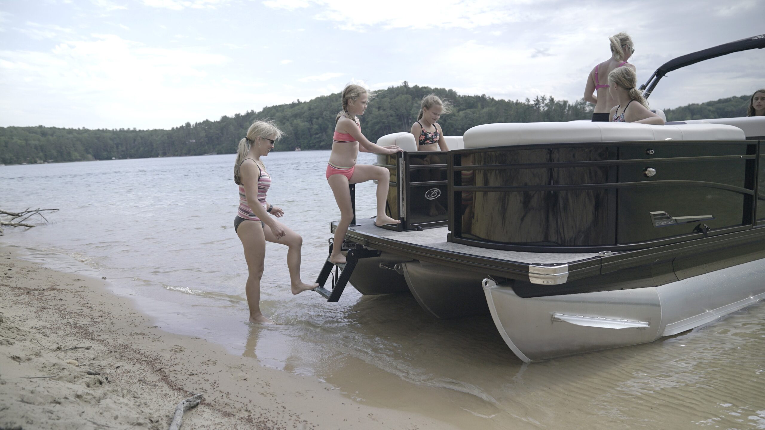 Woman and child boarding pontoon from shore using bow-mounted LilliPad™ Beach Ladder